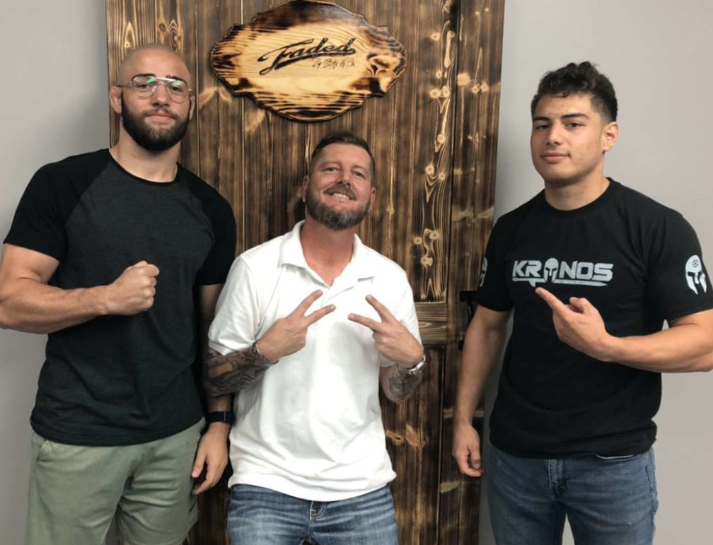 Stylz posing under the Faded sign between two other men.