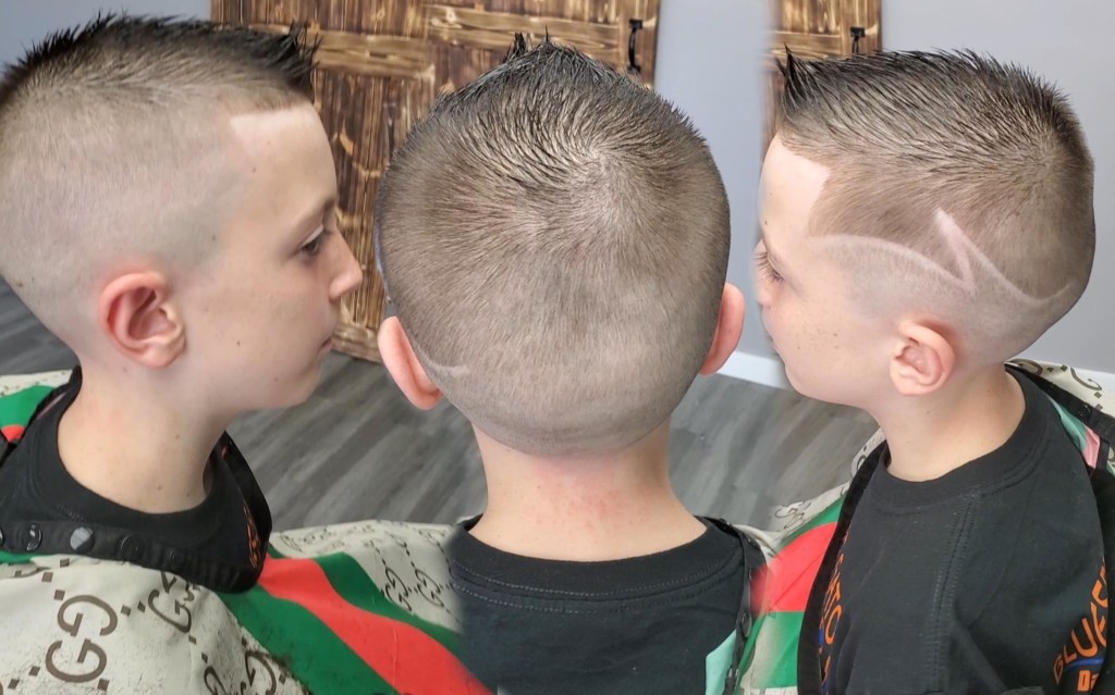 A child with a fresh haircut. A zig-zag has been shaved into the left side of their head.