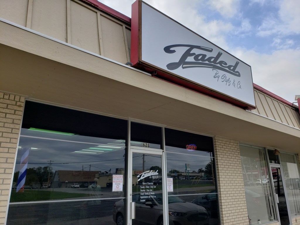 The Faded by Stylz & Co storefront featuring the overhead sign in front of a blue sky.