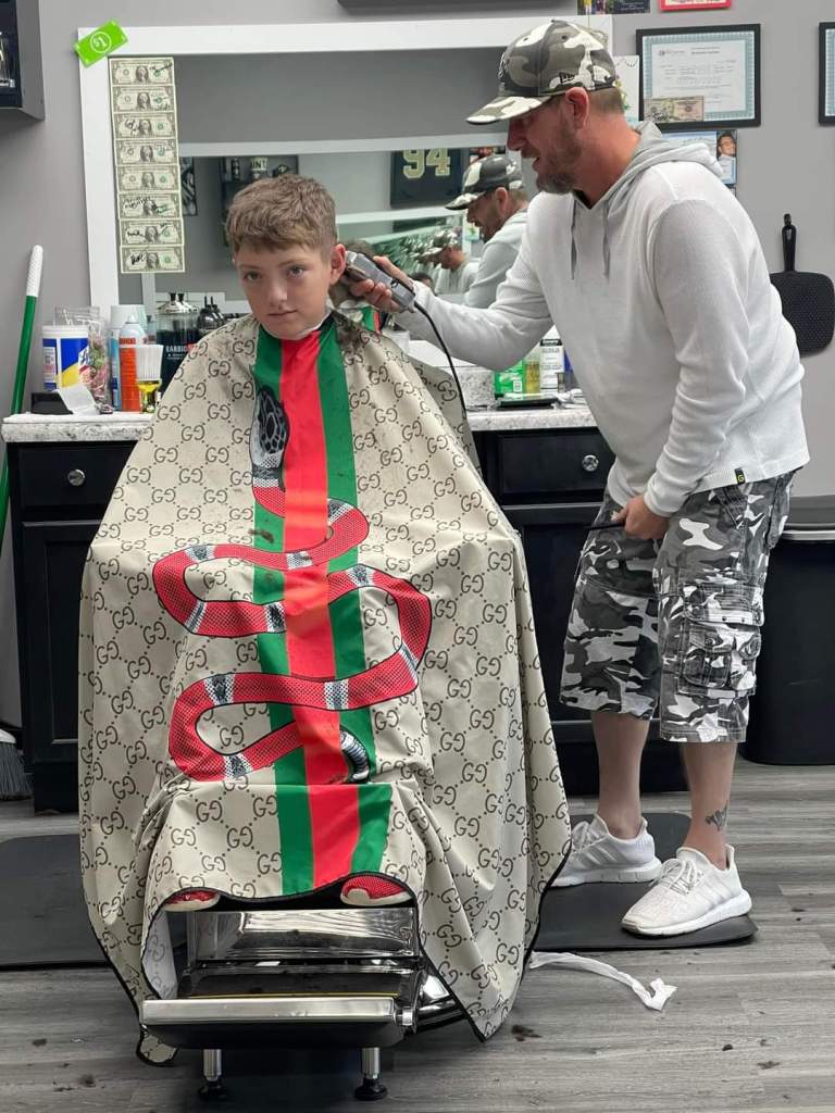 Stylz cutting the hair of a middle-school aged boy.