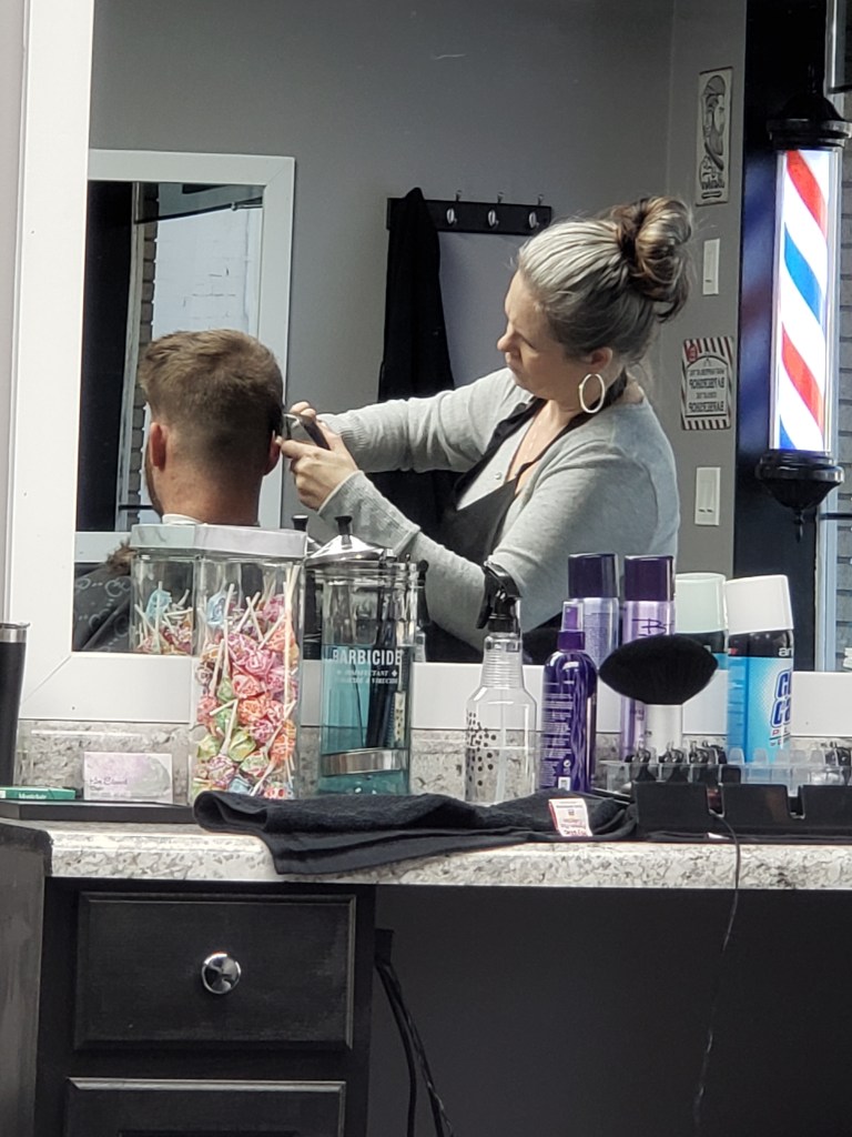 Kim cutting a man's hair.